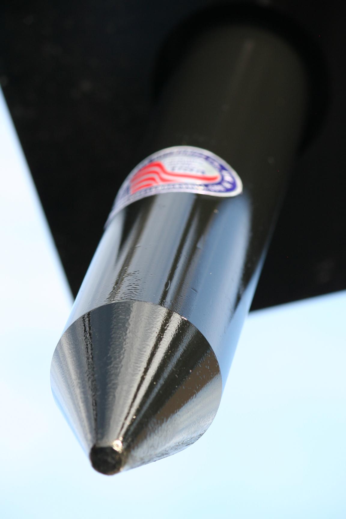 Close-up front view of a polished conical moil point tool bit for a hydraulic breaker, showing the tapered tip and USA-made certification sticker